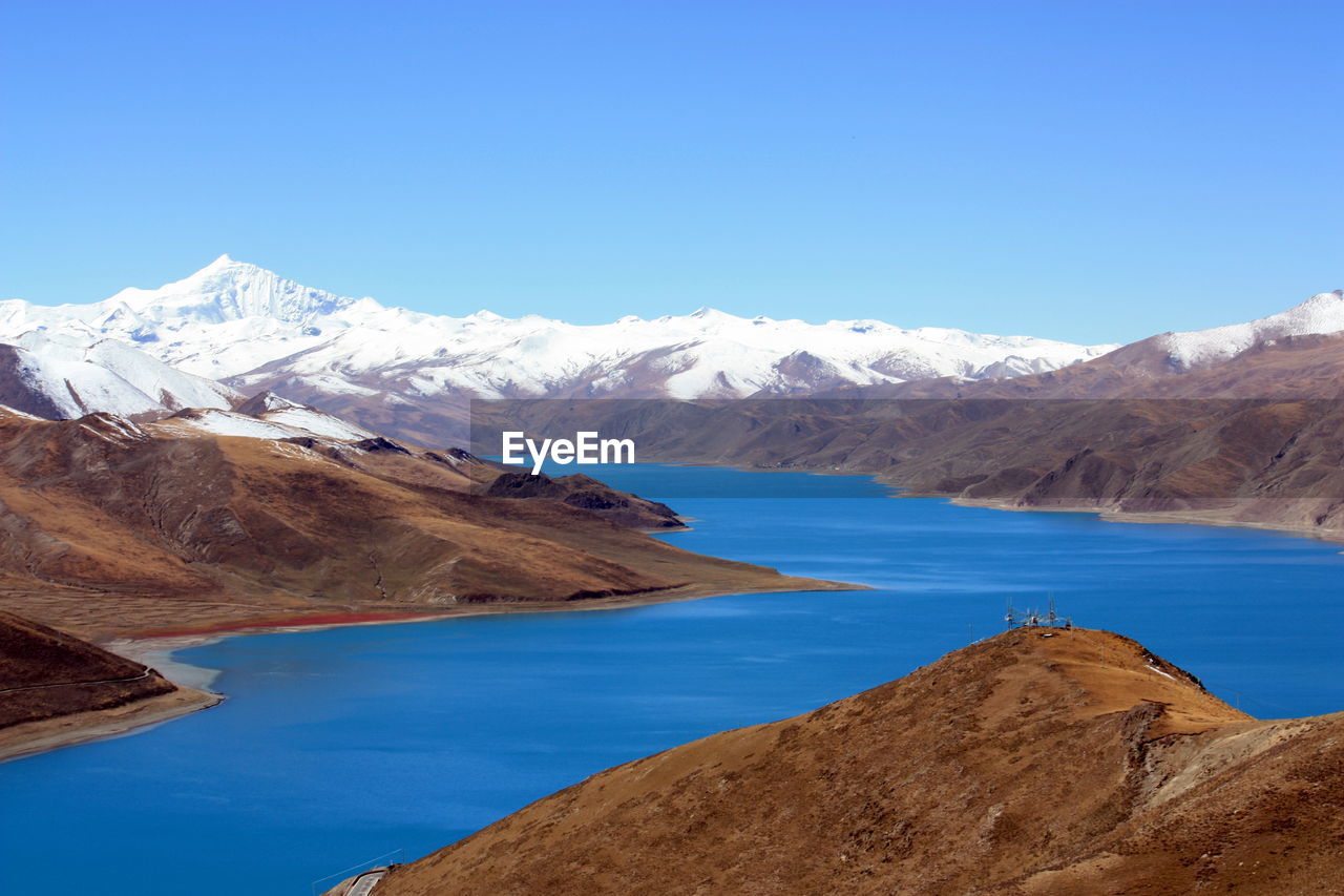 Scenic view of lake and mountains against clear blue sky