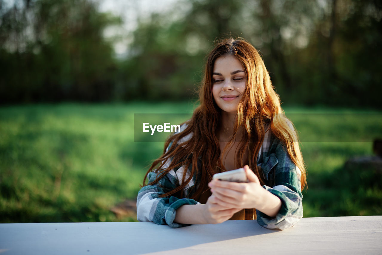 portrait of smiling young woman sitting on field