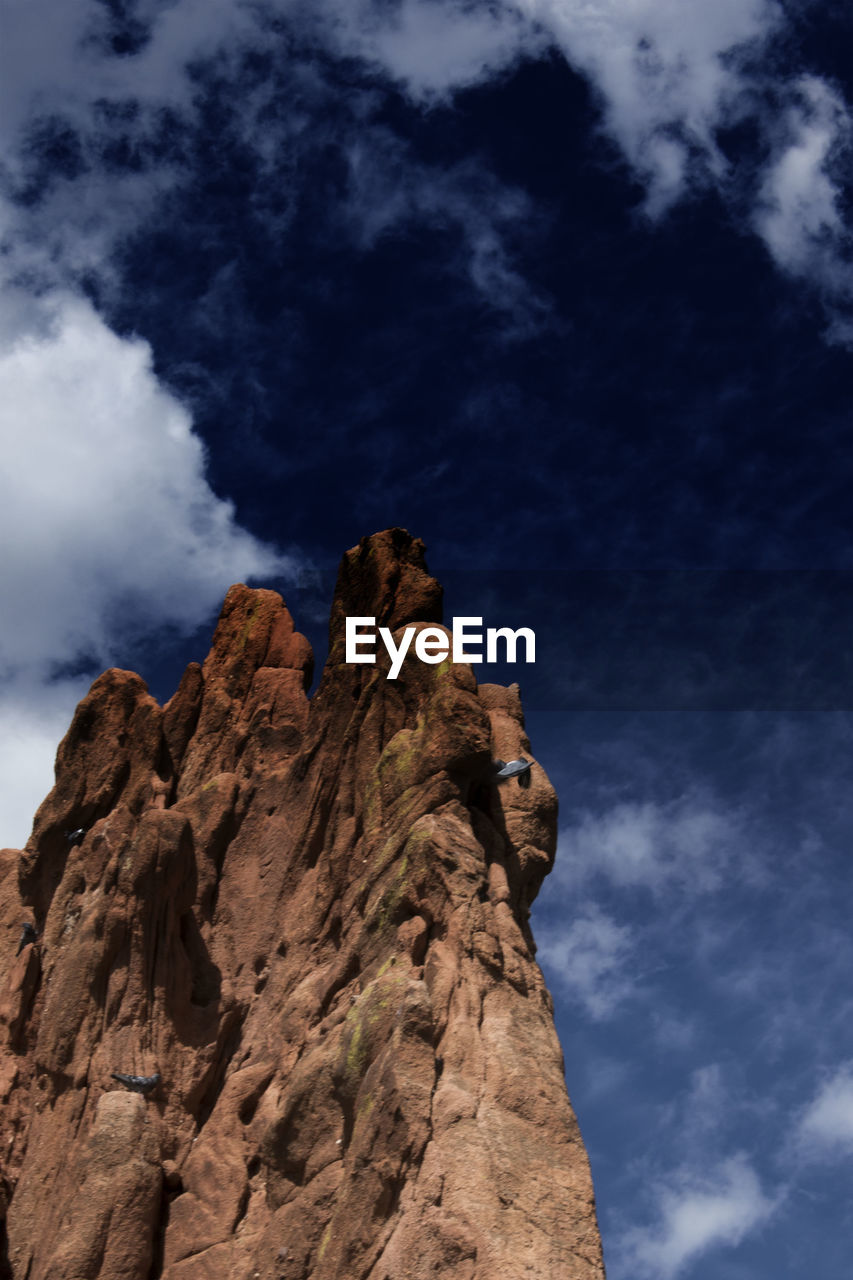 Low angle view of rock formations against cloudy sky