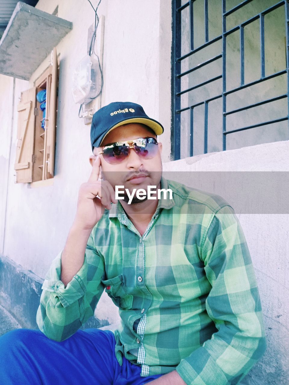 YOUNG MAN WEARING SUNGLASSES AGAINST WALL