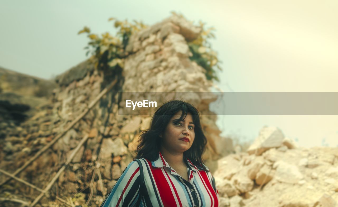 Portrait of beautiful young woman against sky