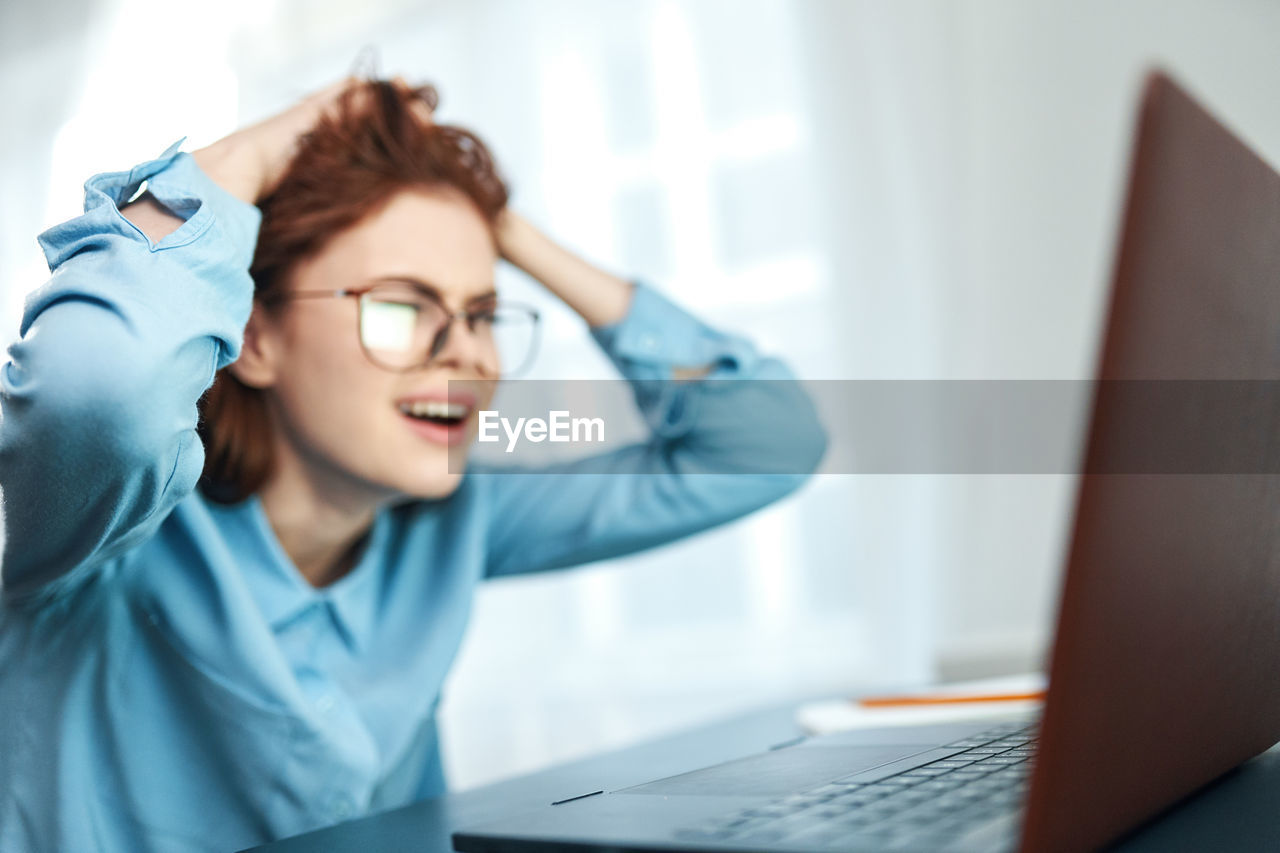 Rear view of woman using phone while sitting on table