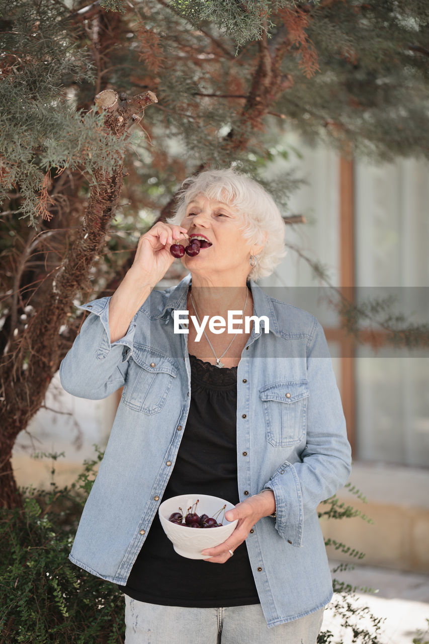 Elderly woman holding a bowl of ripe cherries