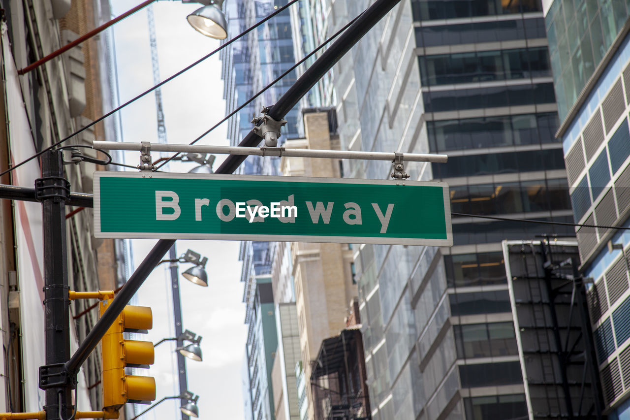 Low angle view of directional sign amidst buildings