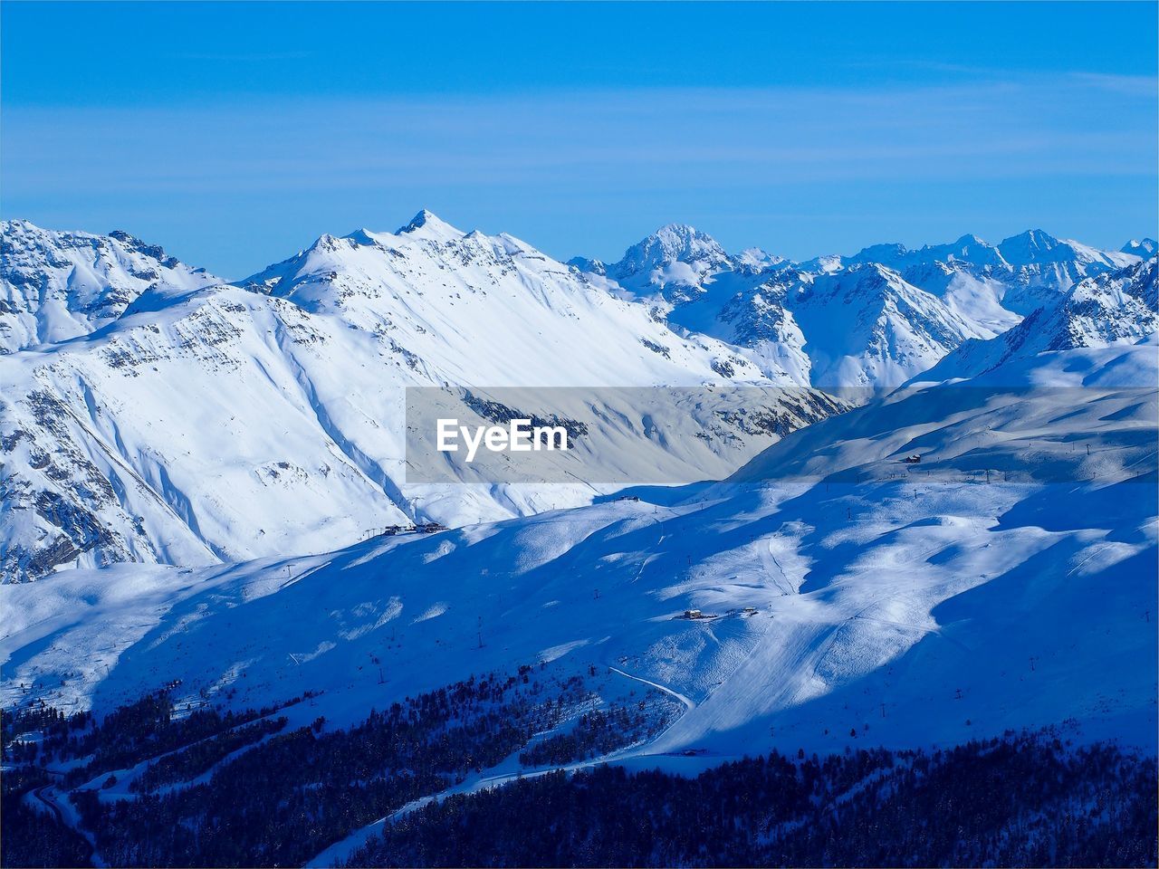 Scenic view of snowcapped mountains against blue sky