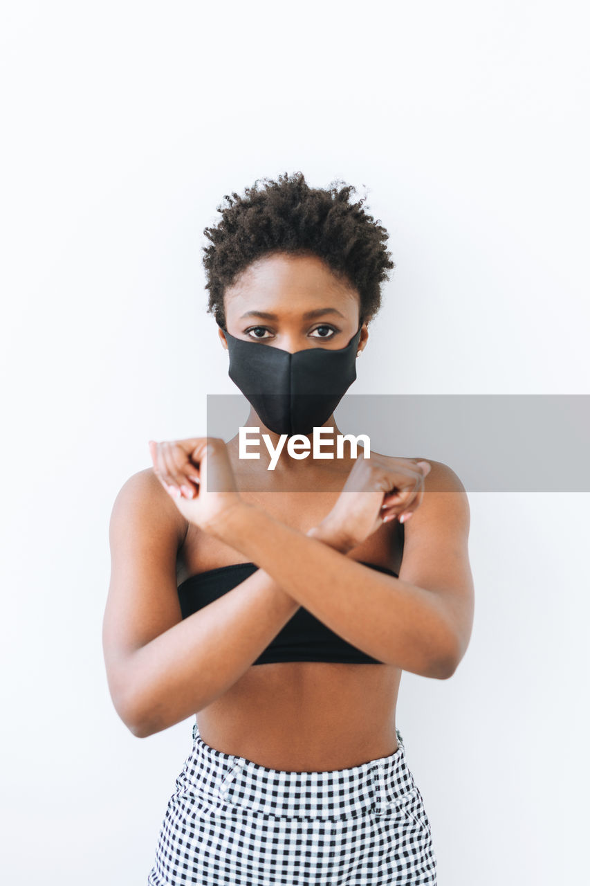 Beautiful young african american woman in black top and face mask isolated on the white background