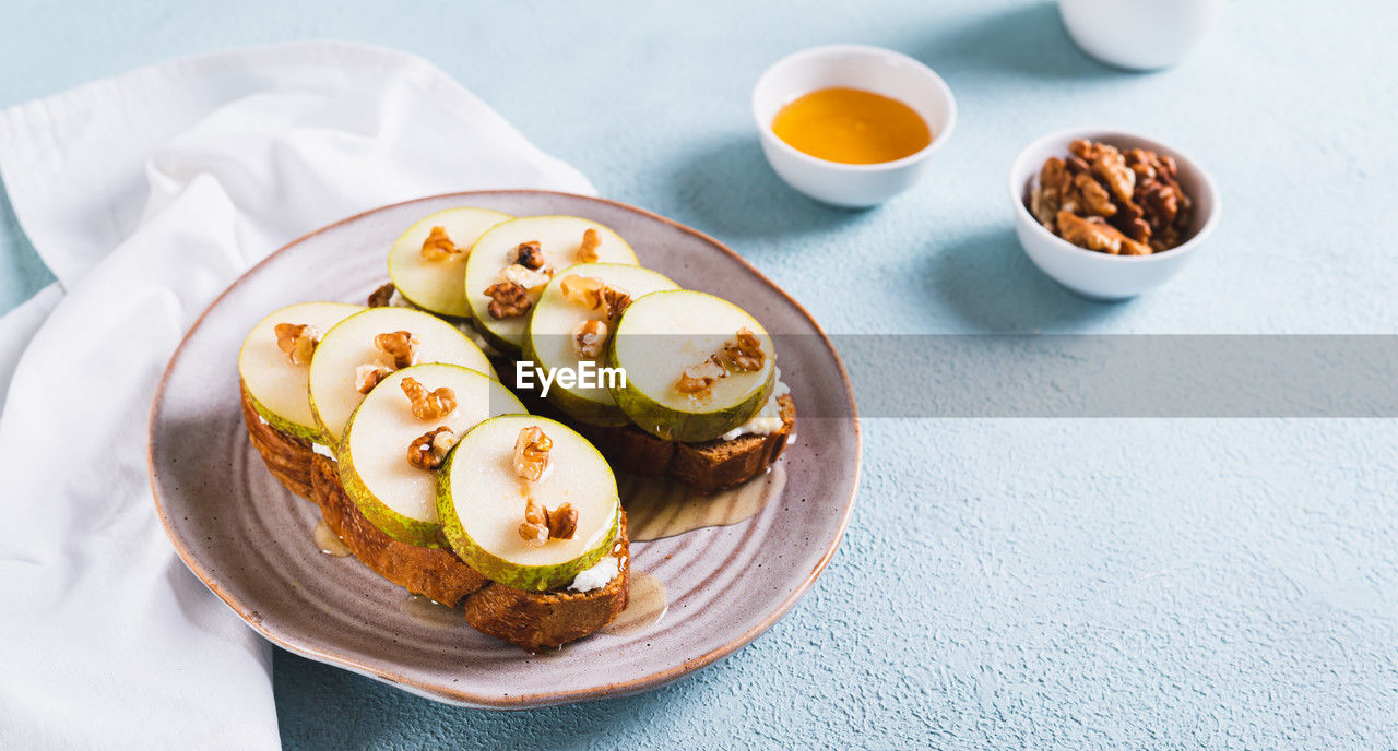 Appetizing sandwiches on rye bread with arugula, pear, honey and nuts on a plate web banner