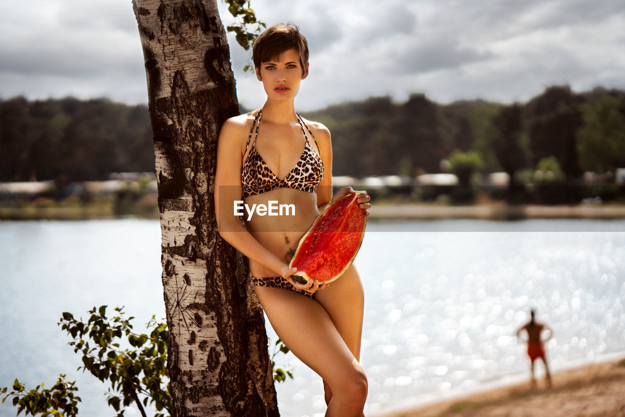 Portrait of model in bikini posing with watermelon at beach