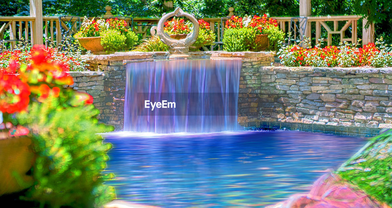 water, plant, nature, backyard, flower, waterfall, flowering plant, beauty in nature, water feature, garden, multi colored, fountain, no people, motion, ornamental garden, outdoors, travel destinations, pond, architecture, day, swimming pool, formal garden, splashing, front or back yard, blurred motion, freshness, tranquility, flowing water, long exposure