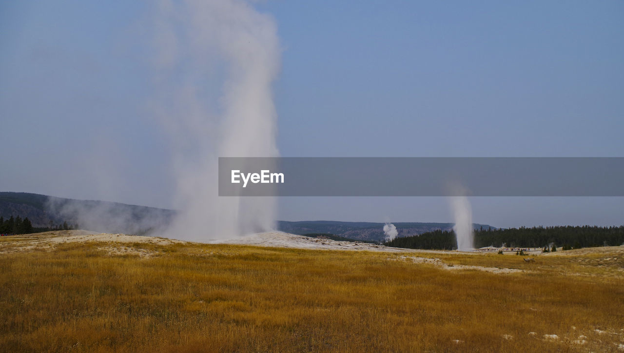 Steam emitting from volcanic landscape against clear sky