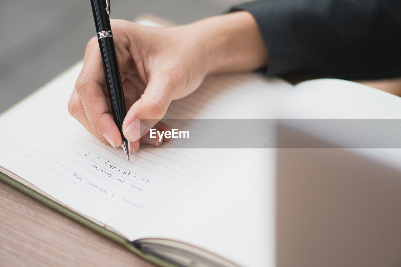 midsection of woman writing in book