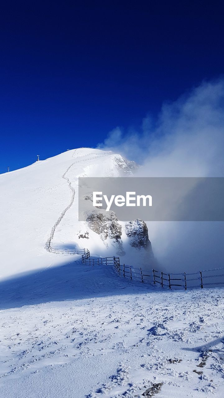 SCENIC VIEW OF SNOW COVERED LANDSCAPE AGAINST BLUE SKY