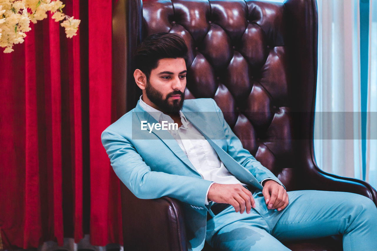 Young man looking away while sitting on seat