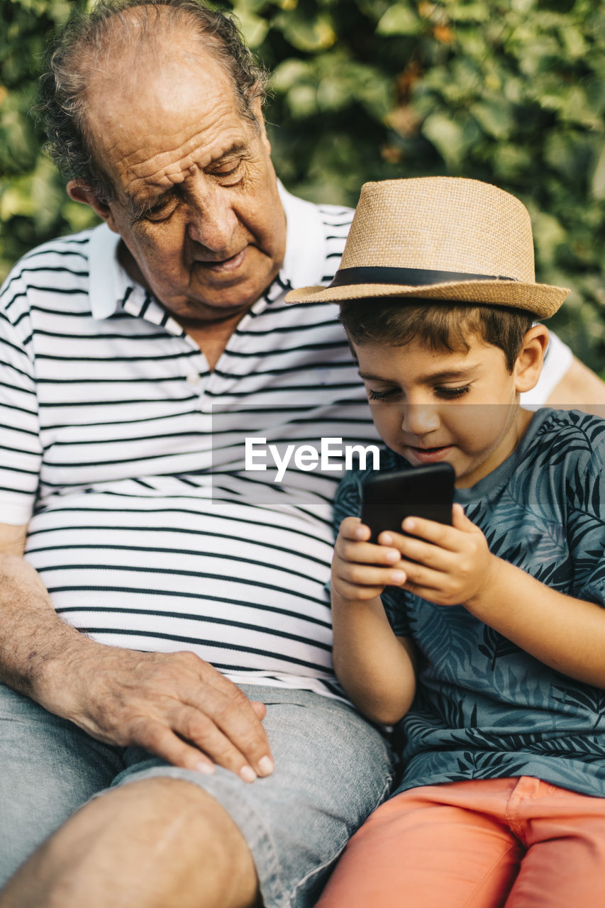 MATURE MAN USING MOBILE PHONE WHILE SITTING ON LAPTOP IN SMART