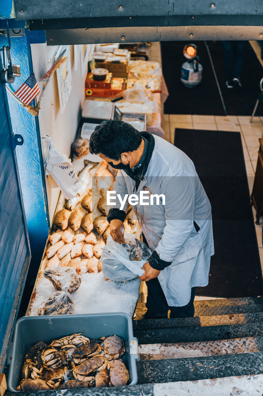 HIGH ANGLE VIEW OF MAN WORKING ON MARKET