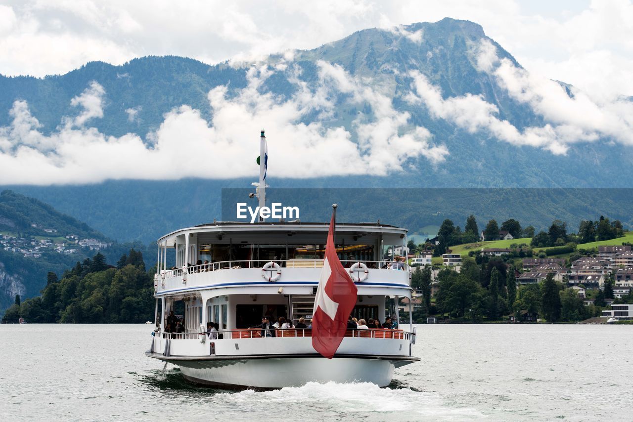 Boat sailing on river against mountain