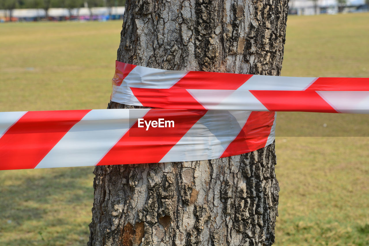 CLOSE-UP OF RED UMBRELLA ON WOODEN POST