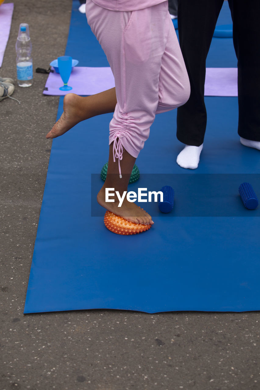 Low section of woman standing on spiked balls while exercising in gym