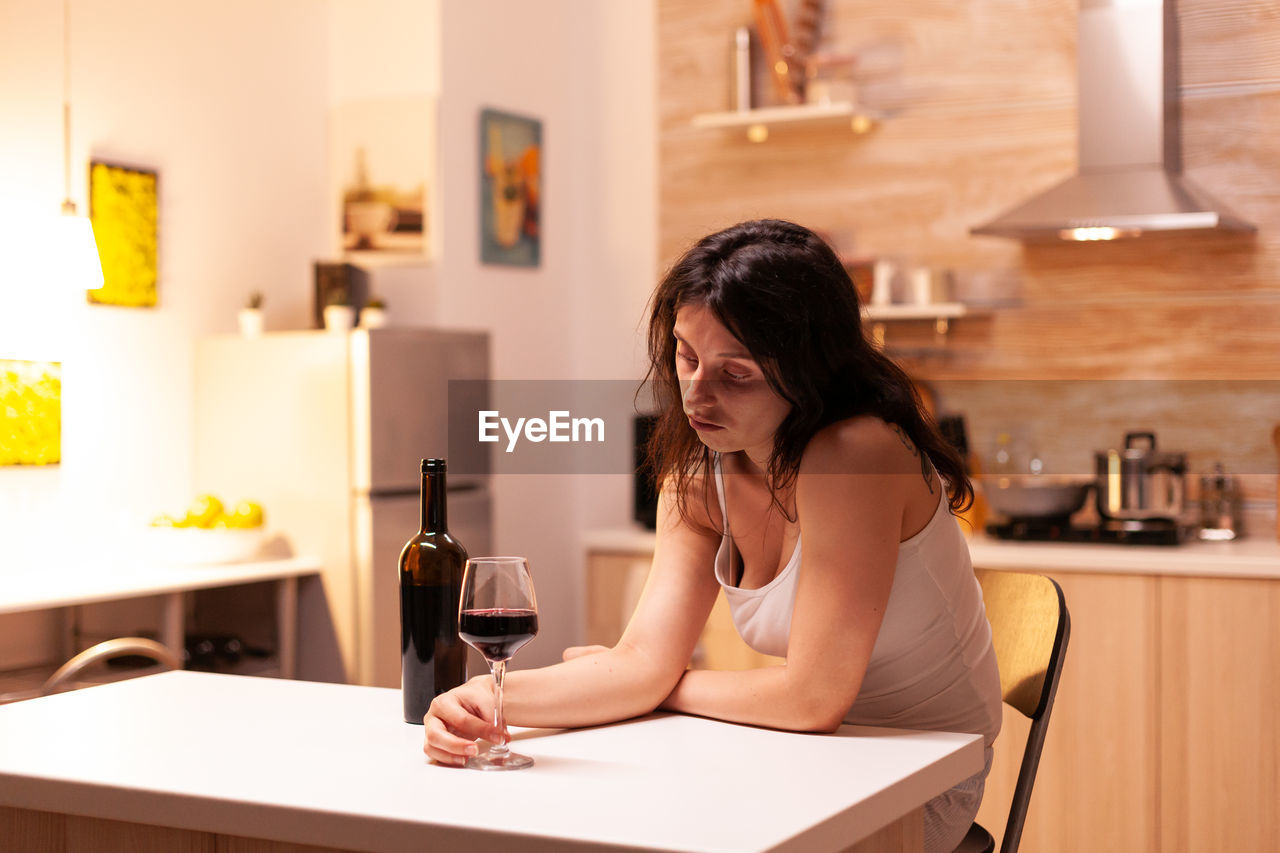 young woman using mobile phone while sitting at table