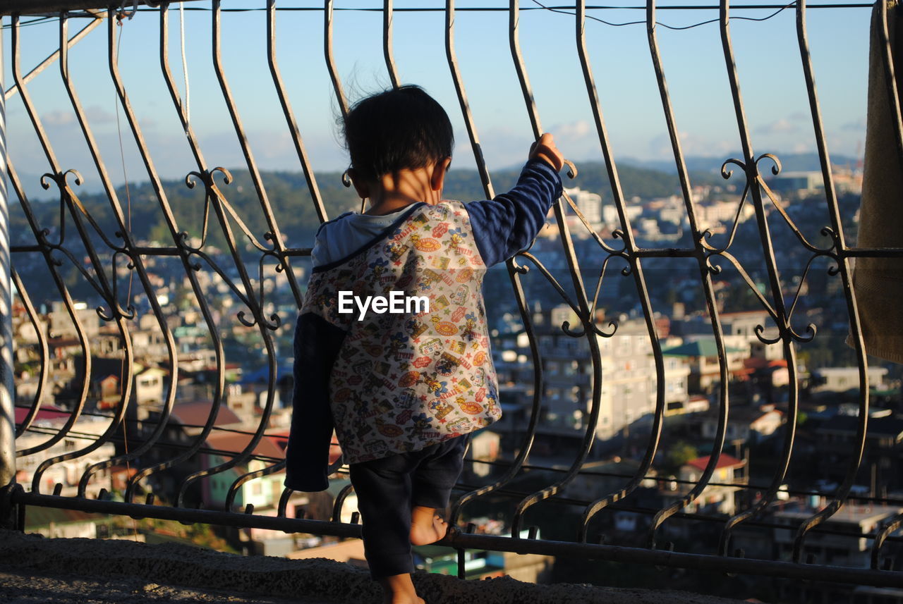 Rear view of child standing by railing