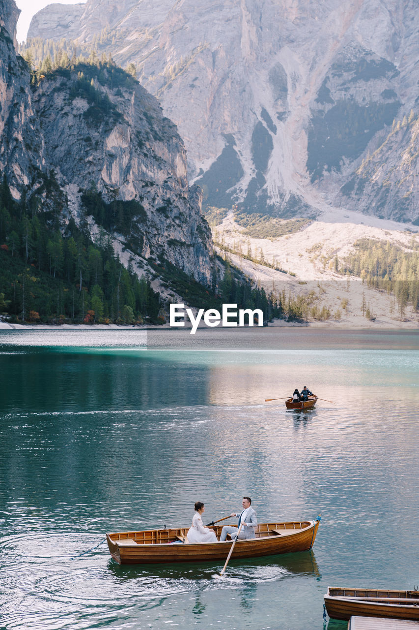 VIEW OF BOATS IN LAKE AGAINST MOUNTAINS