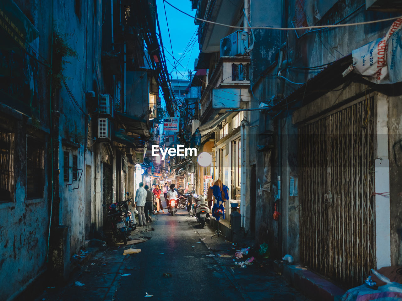 PEOPLE ON STREET AMIDST ILLUMINATED BUILDINGS AT NIGHT