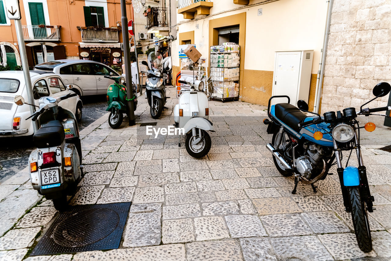 BICYCLES PARKED ON STREET AMIDST BUILDINGS