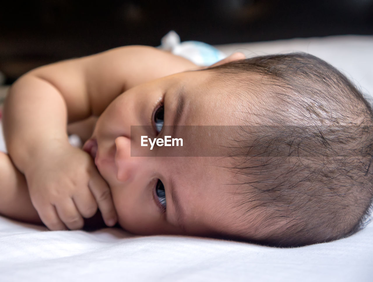 CLOSE-UP PORTRAIT OF CUTE BABY LYING ON BED