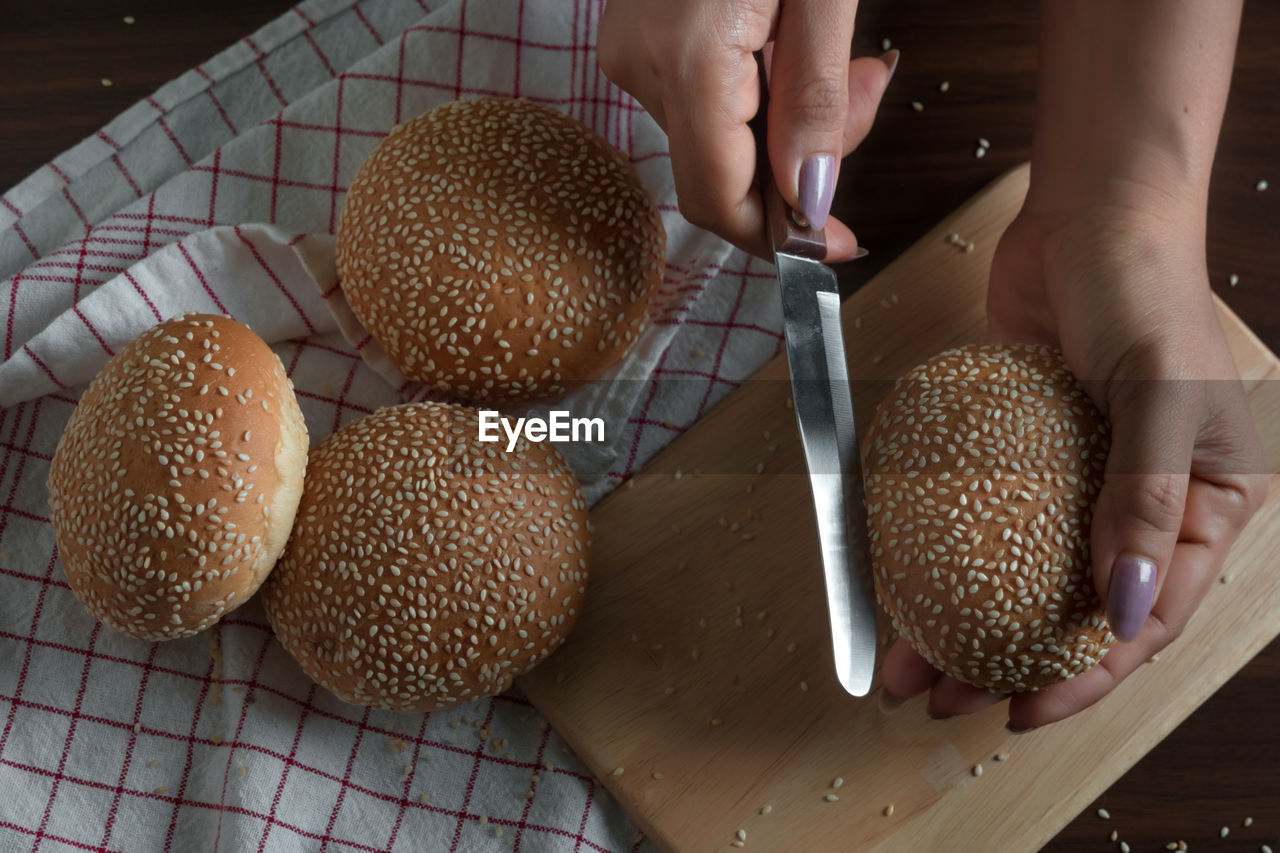 Cropped hands of woman cutting sesame seed buns