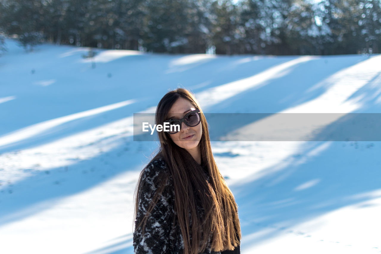 Portrait of smiling woman standing on snow covered land