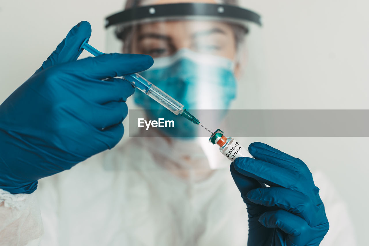 Close-up of doctor injecting syringe in vial at hospital