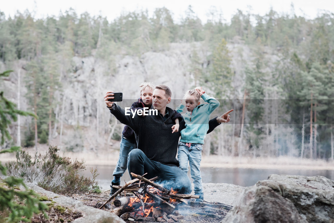 Father taking selfies with his kids whilst sitting next to a campfire