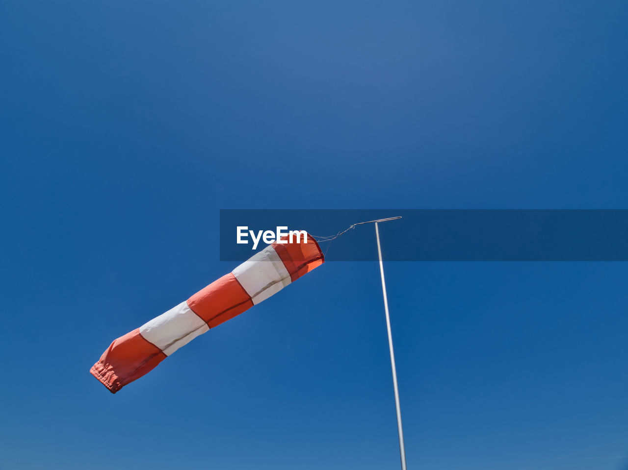 Low angle view of windsock against clear blue sky