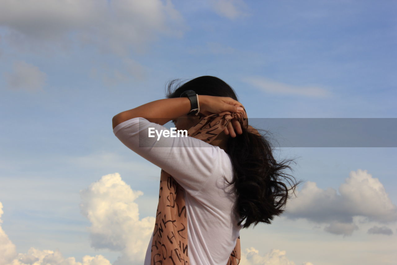 Side view of woman standing against sky