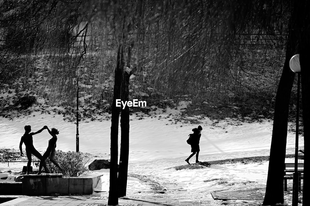 Person walking snow covered landscape and statue 