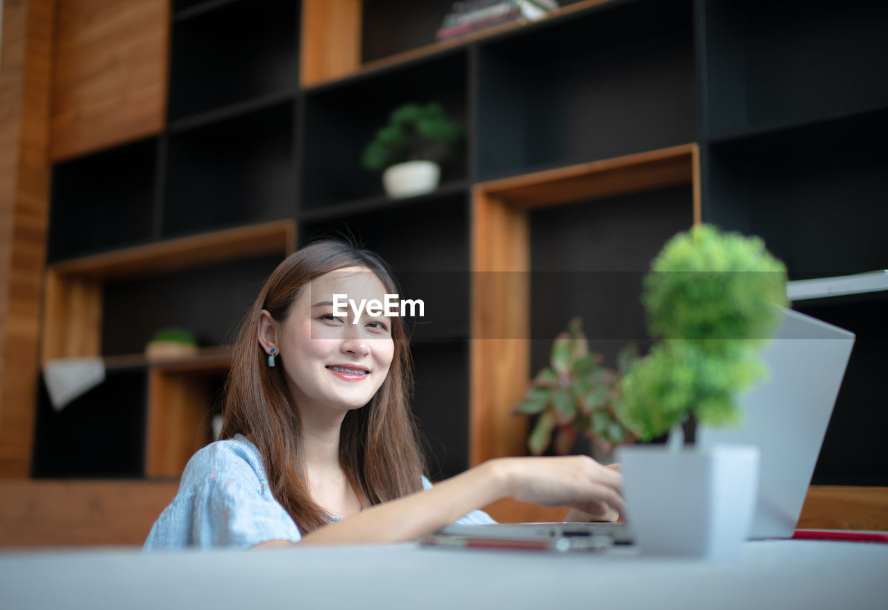Portrait of smiling woman using laptop on sofa at home