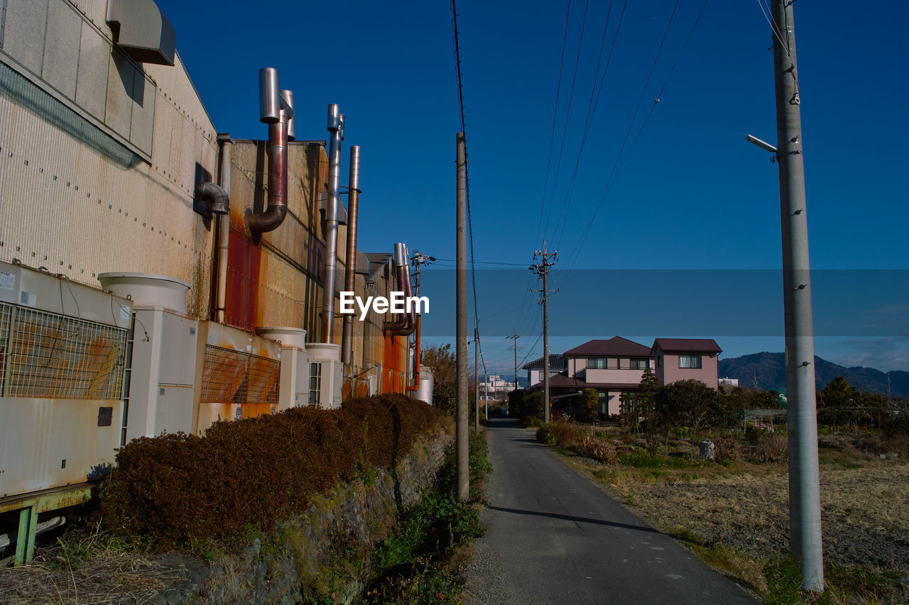 Street amidst buildings against clear blue sky