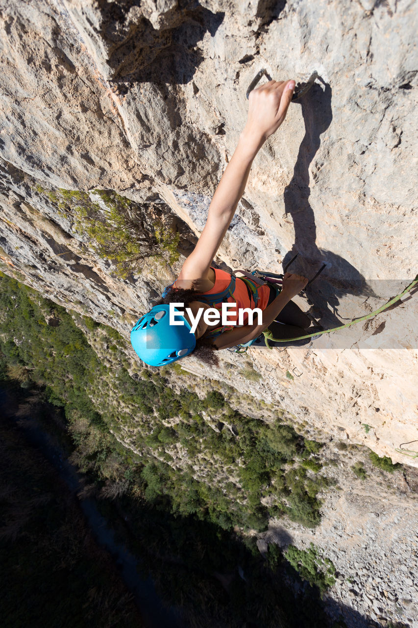 Young woman climbing through a via ferrata in chulilla canyon (spain)