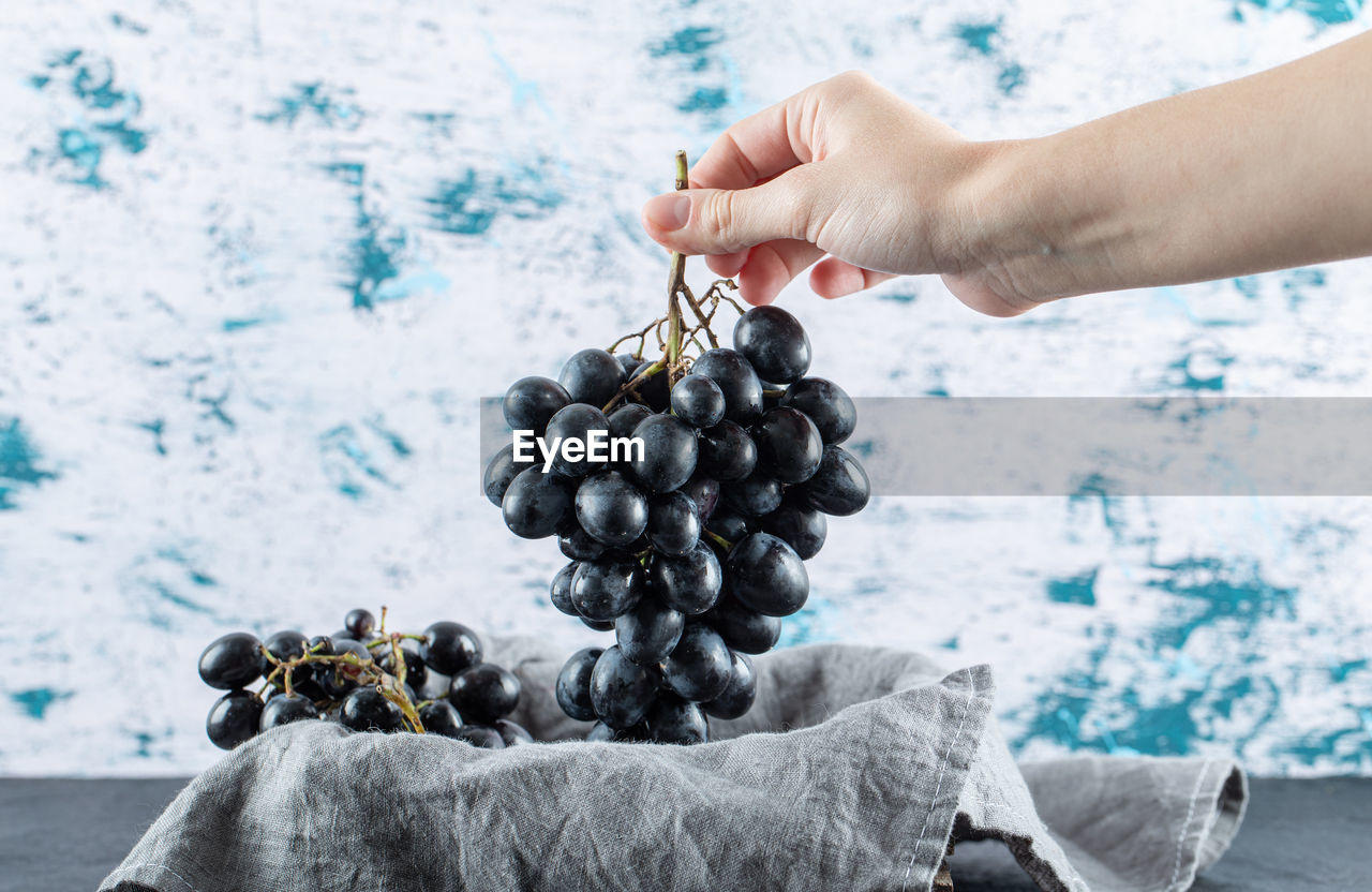 CLOSE-UP OF PERSON HOLDING GRAPES