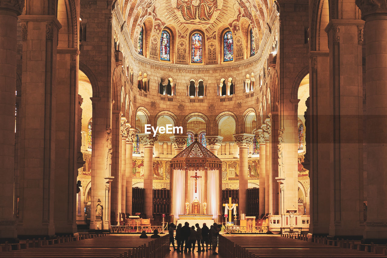 Low angle view of the center alley of a basilica, with silhouettes.
