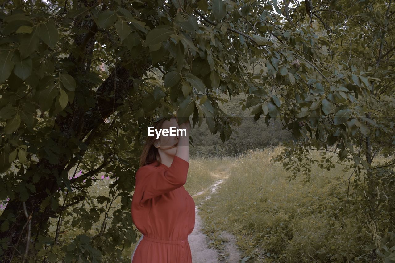 Portrait of woman standing against trees