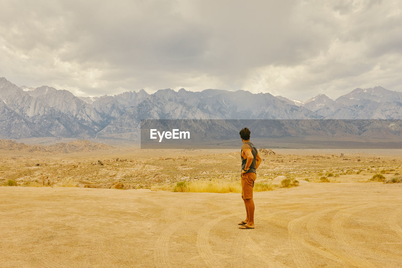 Young man in the california desert looking mountains of alabama hills.