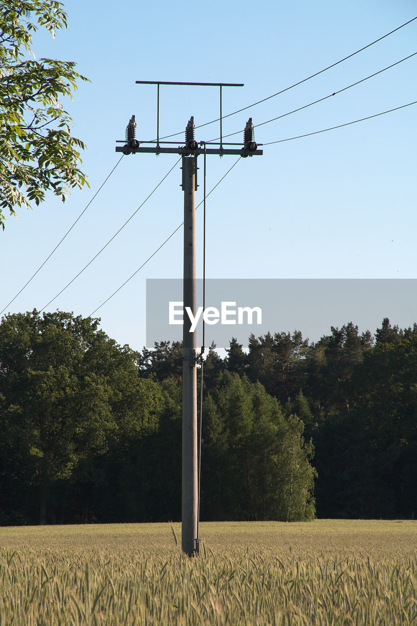 LOW ANGLE VIEW OF ELECTRICITY PYLONS ON FIELD AGAINST SKY