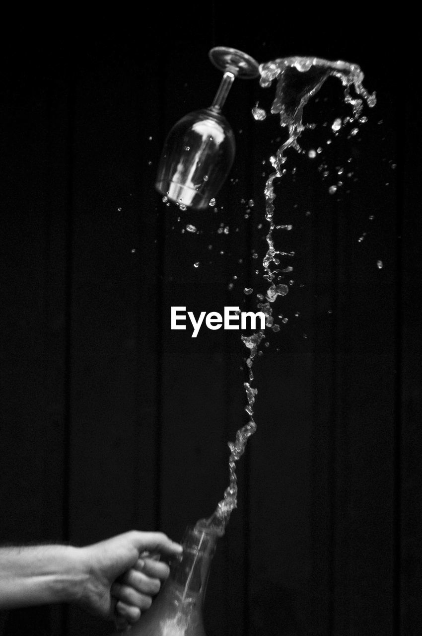 Close-up of hand splashing water against black background