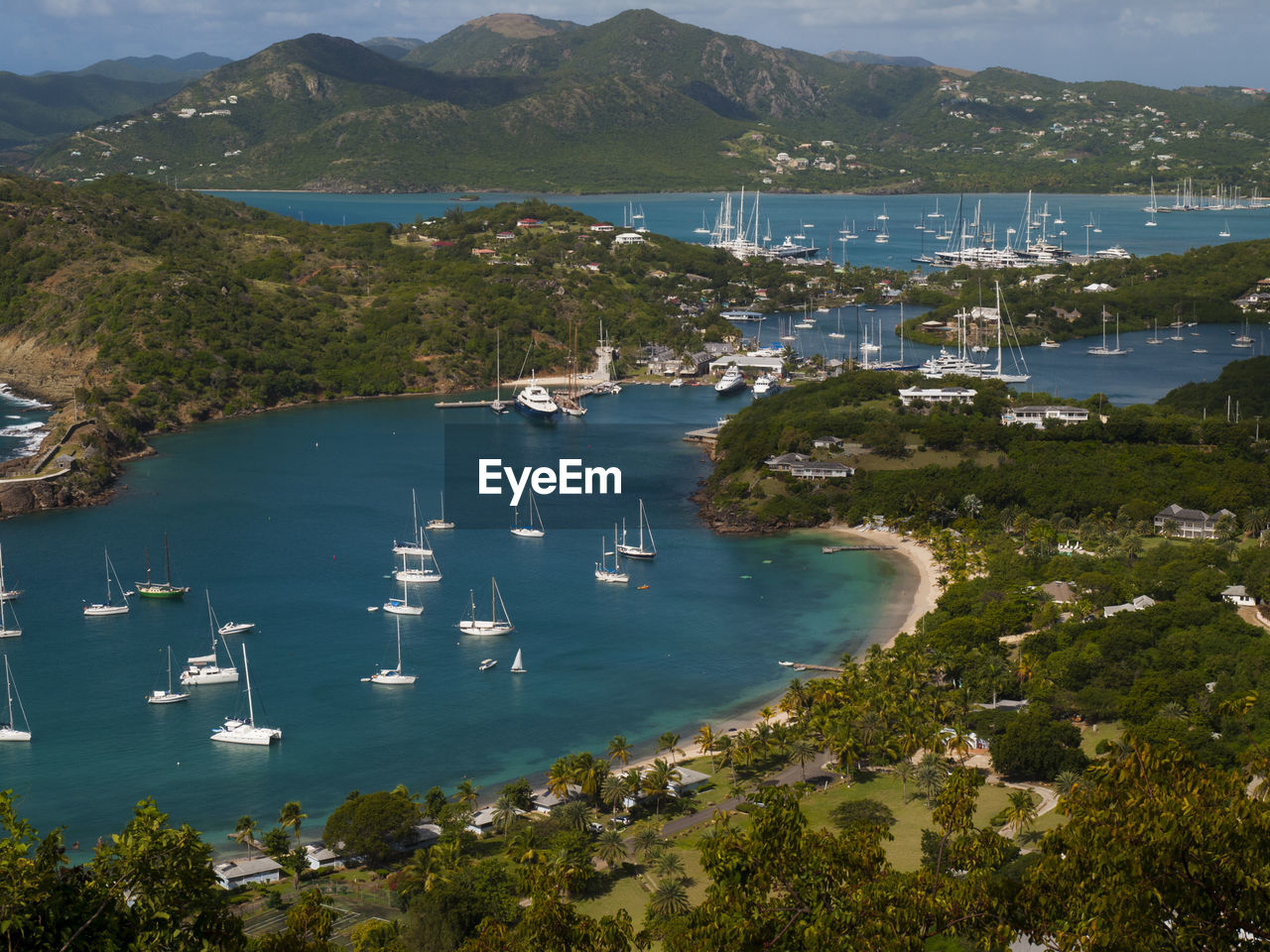 High angle view of sailboats moored on sea by mountains