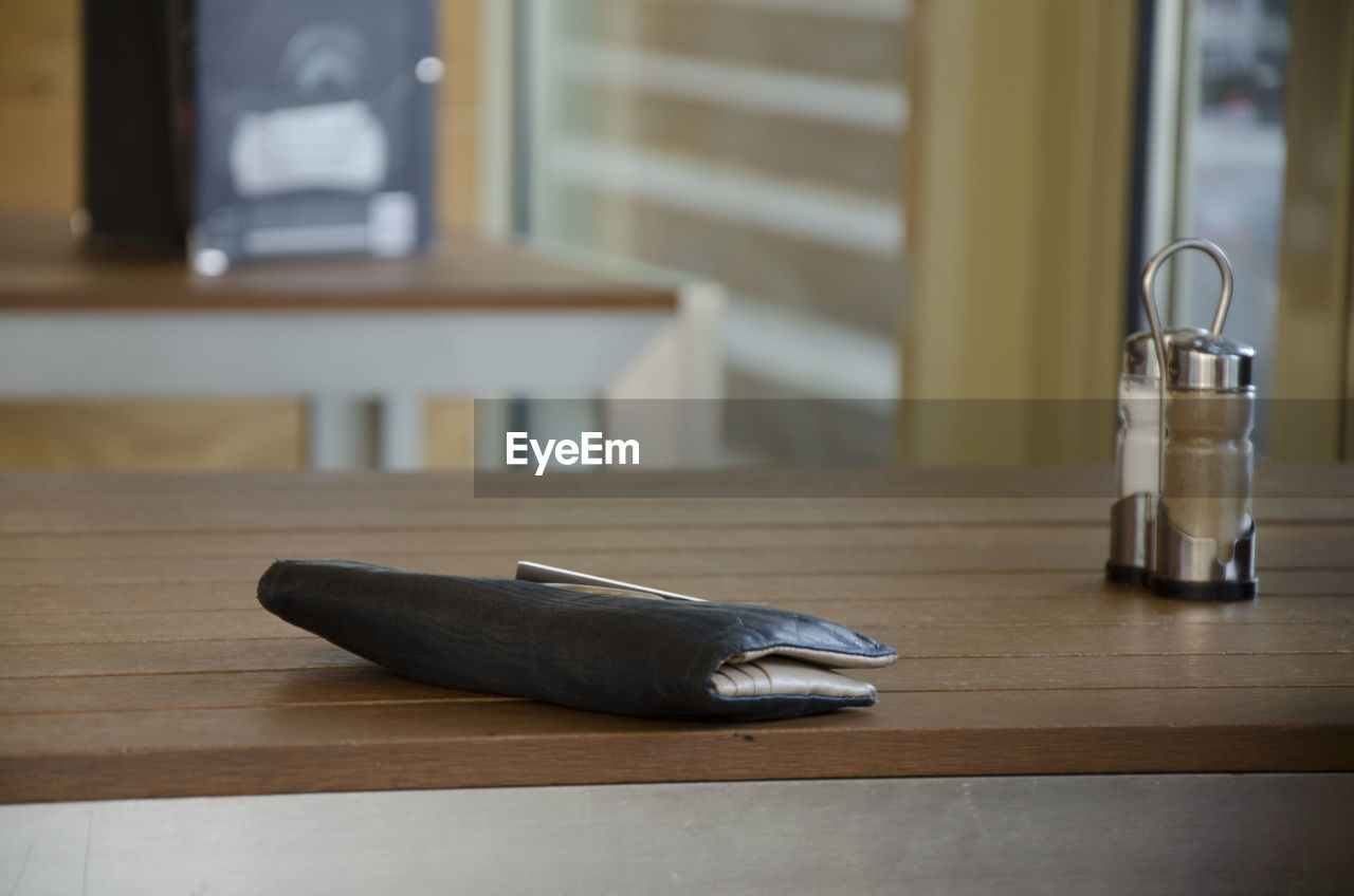 Close-up of wallet next to pepper shaker on table