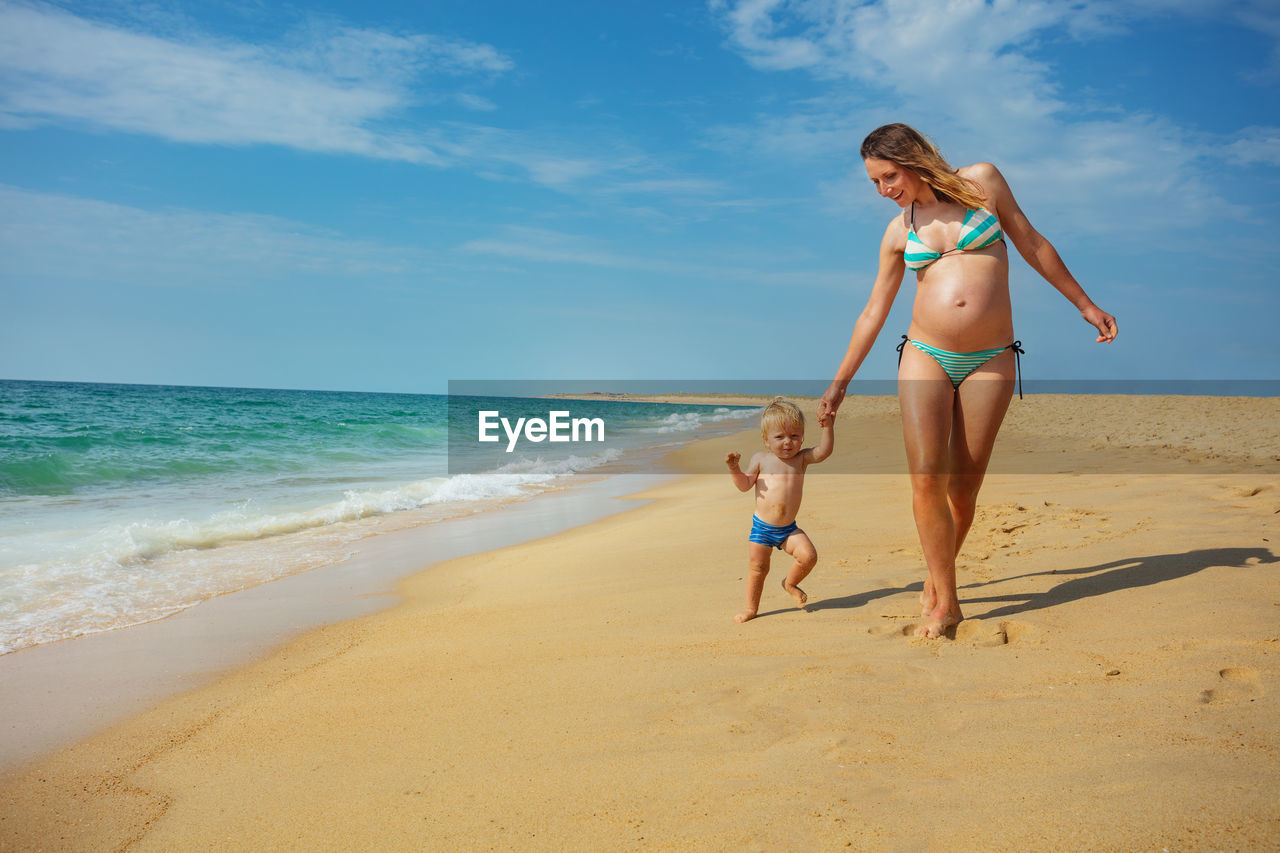 full length of woman standing at beach against sky