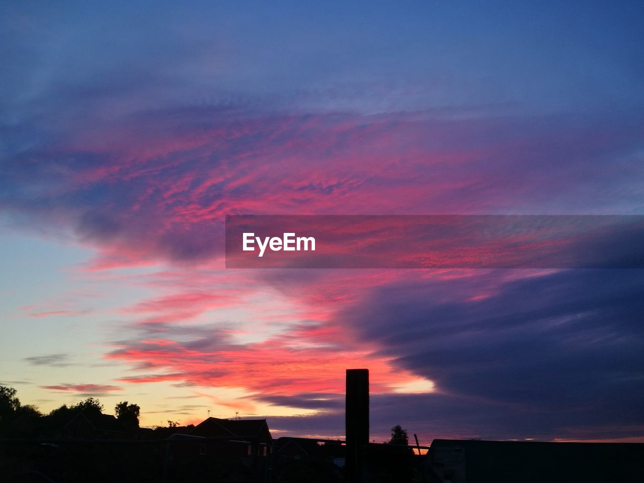 LOW ANGLE VIEW OF SILHOUETTE BUILDINGS AGAINST DRAMATIC SKY DURING SUNSET