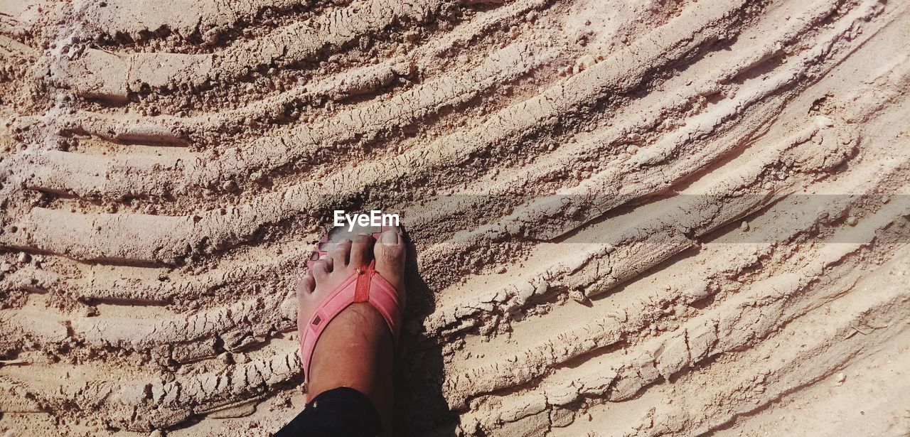 LOW SECTION OF WOMAN WALKING ON SAND