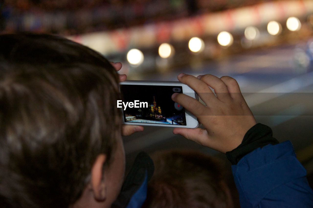 Close-up of boy photographing at night